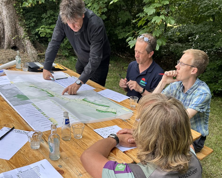 Deelnemers buigen zich over de kaart van Broekenloop / Oostervoortsche Diep waarbij de landschapsontwerper schetst